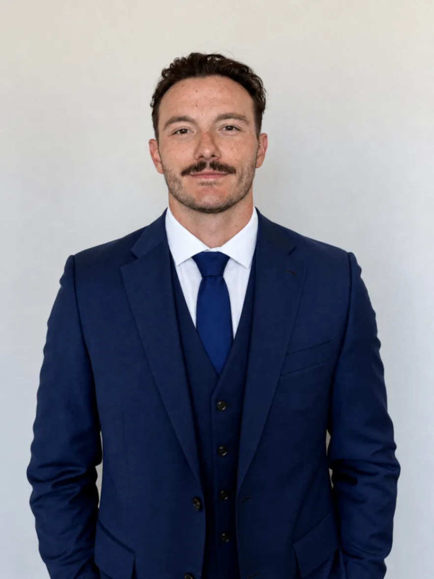 Portrait of Jacob Young in a navy suit and tie against a light background.